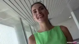 Woman in green dress in front of sea cliff