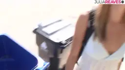 Mujer rubia ríe frente a garaje abierto con top blanco
