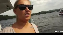 Blonde with sunglasses by the lake, laughing at the camera