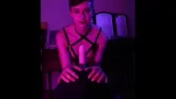 Short black hair, black harness, riding dildo in pink light