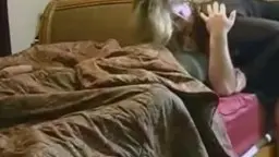 Mature blonde in black bodysuit rides naked man on red sofa