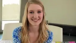 Blonde teen with lowered blouse on white bed