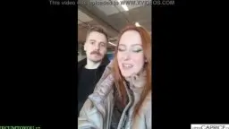 Red-haired girl laughs in selfie, man stands behind her