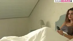 Morena acostada en cama blanca, teléfono en la oreja
