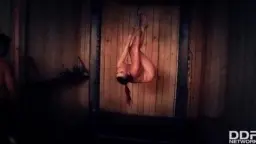 Bound Leila Moon hangs upside down, legs spread, two men beside her.