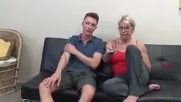 Rubia madura en rojo sentada junto a un chico joven en el sofá