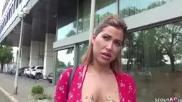 Young woman Heidi in red dress with tattooed cleavage in front of modern building